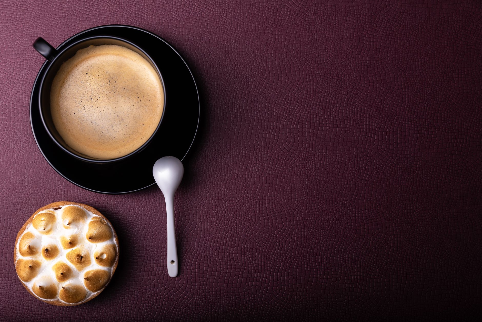 Vue de dessus d'une tasse de café et d'une pâtisserie sur un fond texturé violet avec espace pour le texte.